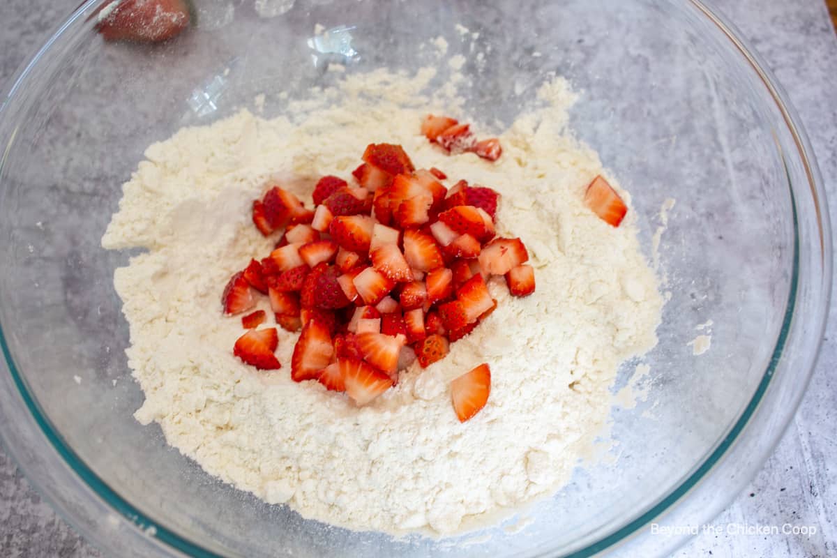 Chopped strawberries on top of a bowlful of flour.