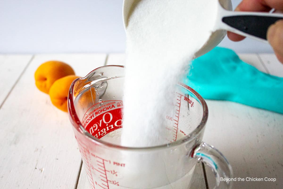 Sugar being poured into a glass measuring cup.