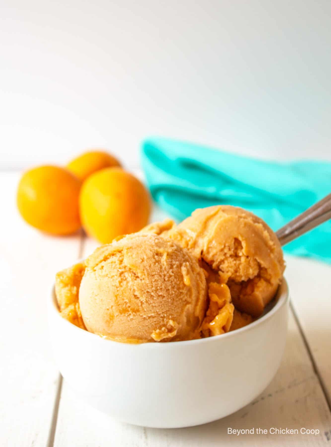 Scoops of apricot sorbet in a white bowl.