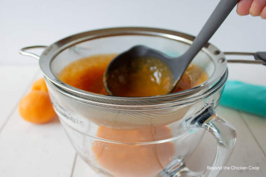 A soup ladle in a pureed apricot mixture.