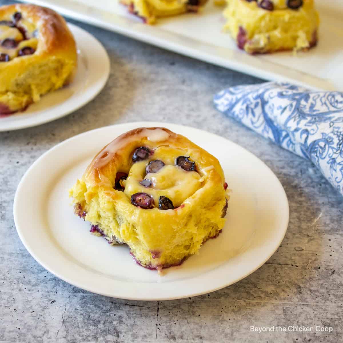 A blueberry lemon cinnamon roll on a white plate.