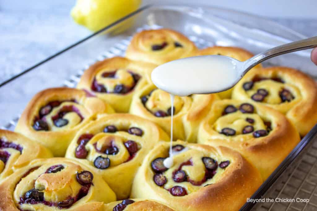 Adding a glaze to blueberry sweet rolls.