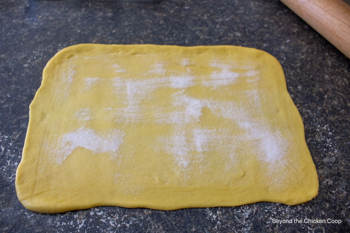 Sweet dough formed into a rectangle on topped with butter and sugar.