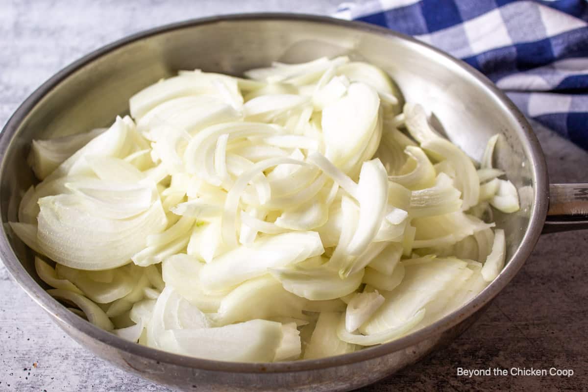 A large pan filled with sliced onions.