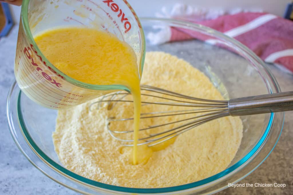 Liquid poured into a bowl filled with a flour mixture.