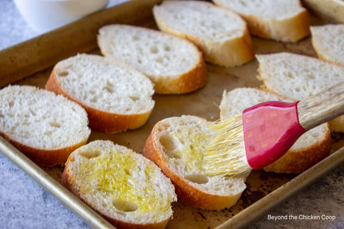 Brushing olive oil onto sliced bread.