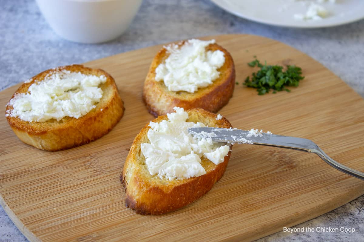 Cheese being spread onto toasted bread.