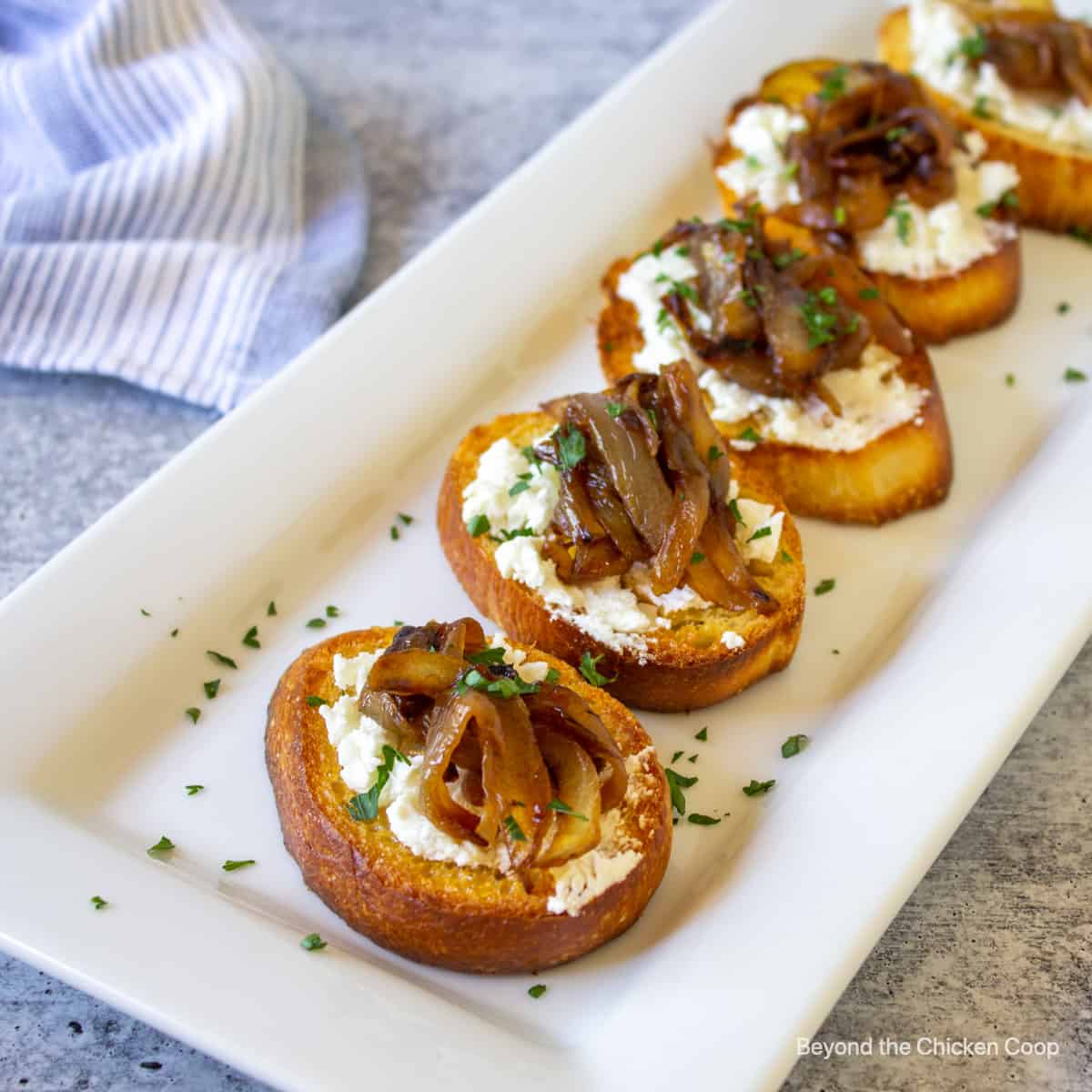 Toasted bread topped with a white spreadable cheese and caramelized onions.