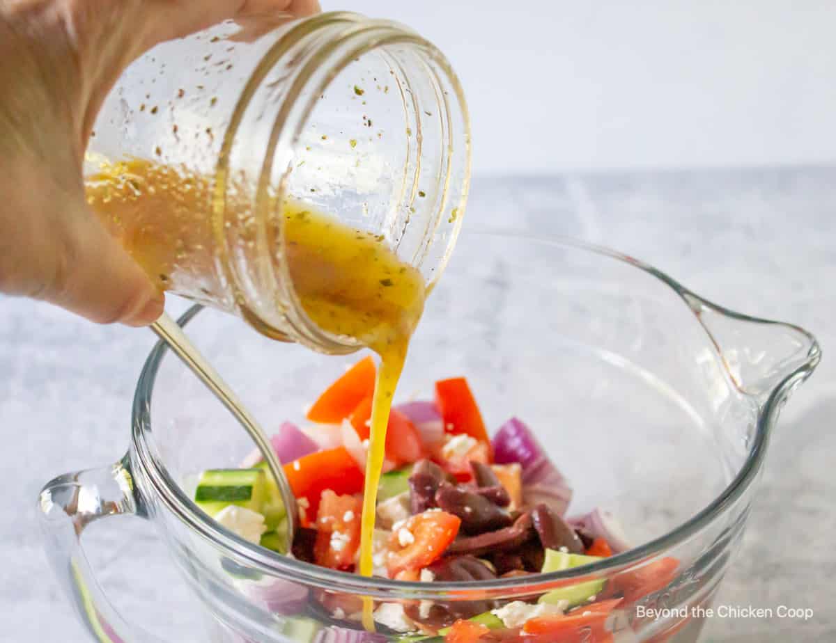 Dressing being poured over freshly cut veggies. 