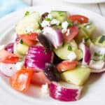 Fresh cut veggies with crumbled cheese on a white plate.