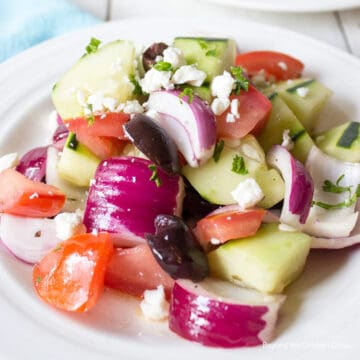 Fresh cut veggies with crumbled cheese on a white plate.