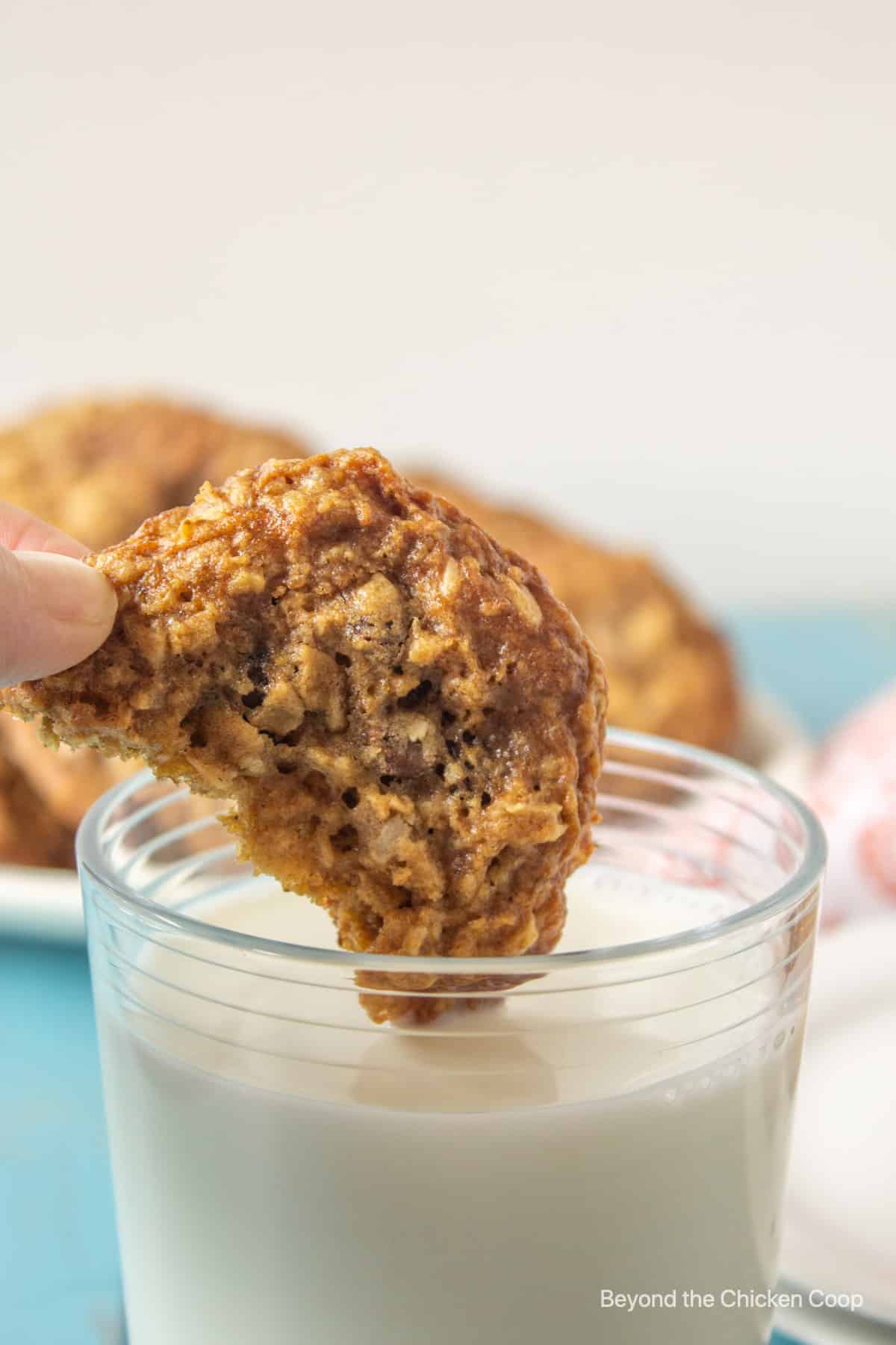 A cookie being dunked into a glass of milk.