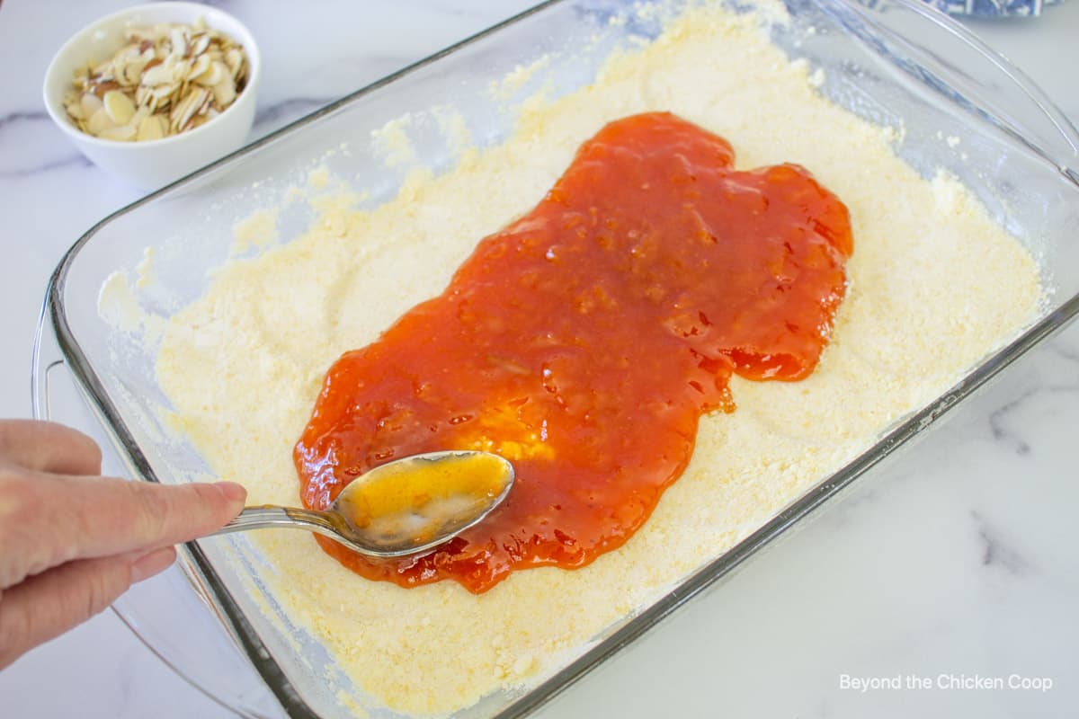 Apricot jam being spread over a crust.
