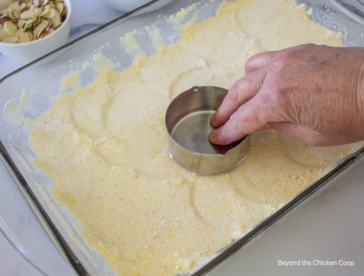 Pressing a crust down into a glass baking dish.