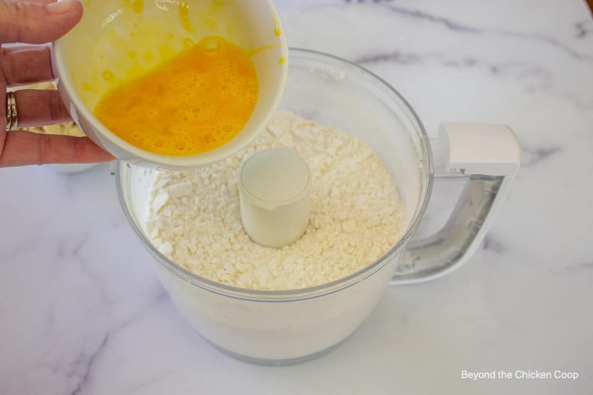 Beaten egg being poured into a flour mixture.