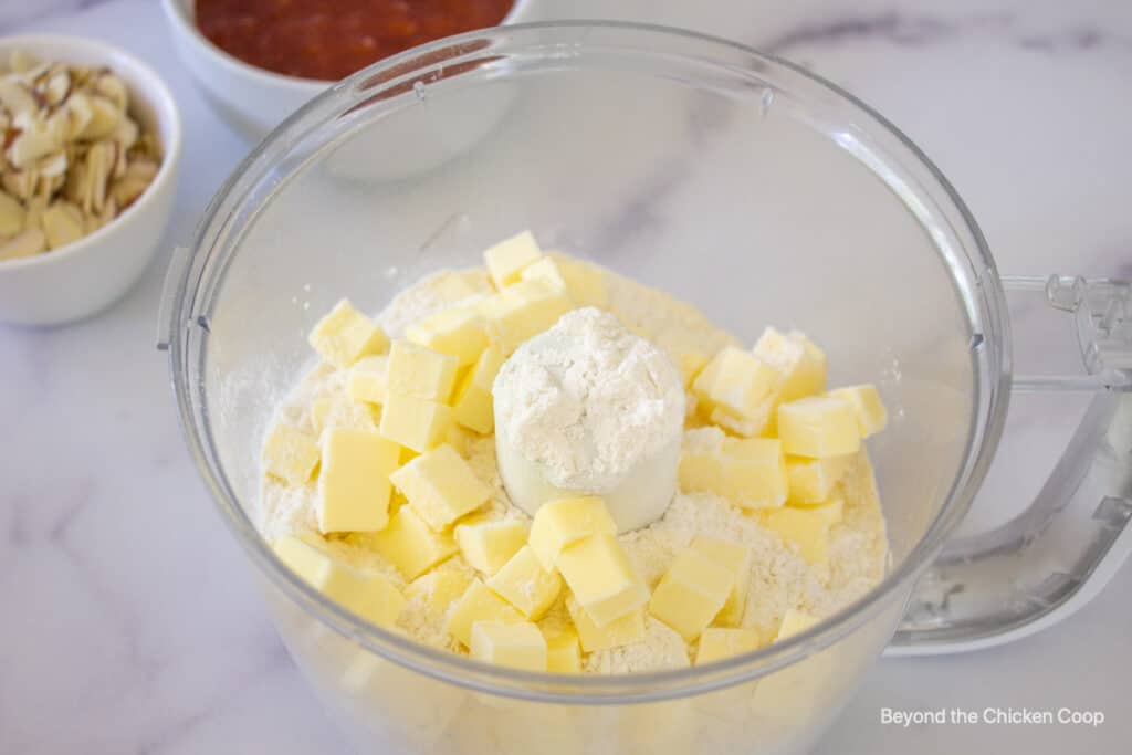 A food processor bowl with flour and butter.