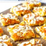 Squares of apricot bars with almonds on a wooden board.