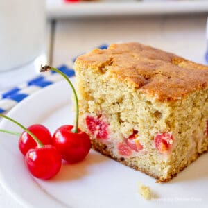 A square piece of cake filled with cherries.