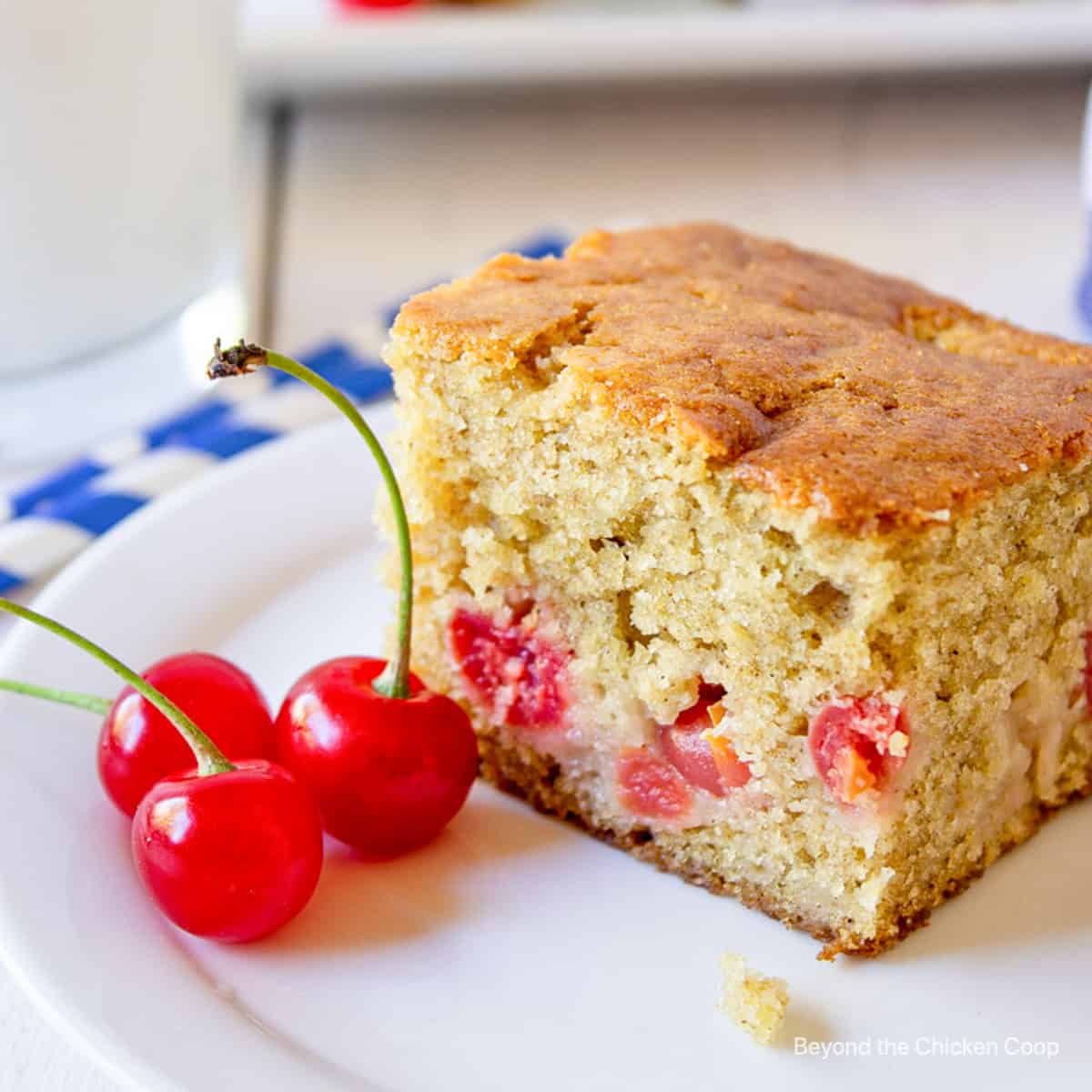 A square piece of cake filled with cherries.