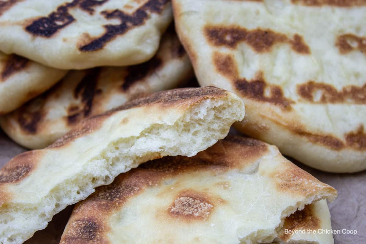 A torn piece of flatbread in a stack of whole flatbreads.