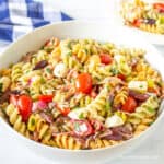 A bowl filled with fussili pasta, tomatoes and cheese.