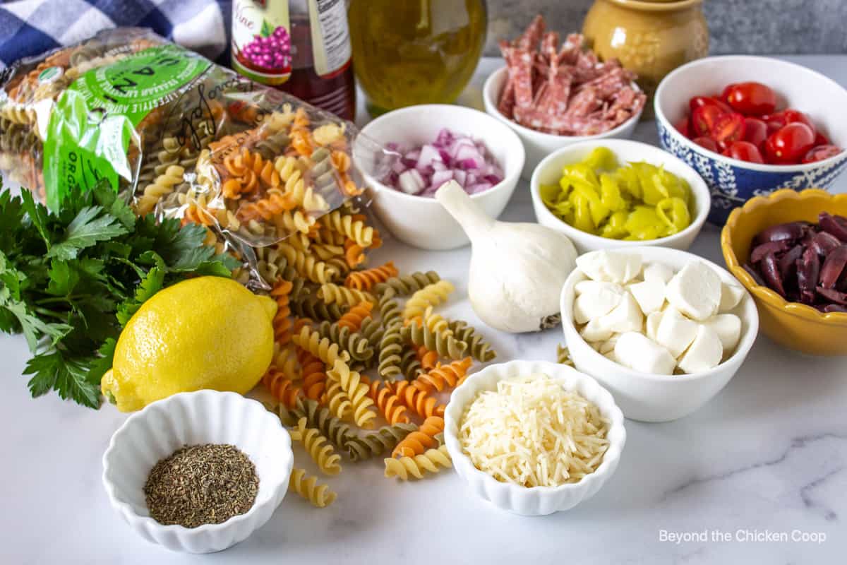 Small bowls filled with different ingredients for making pasta salad.