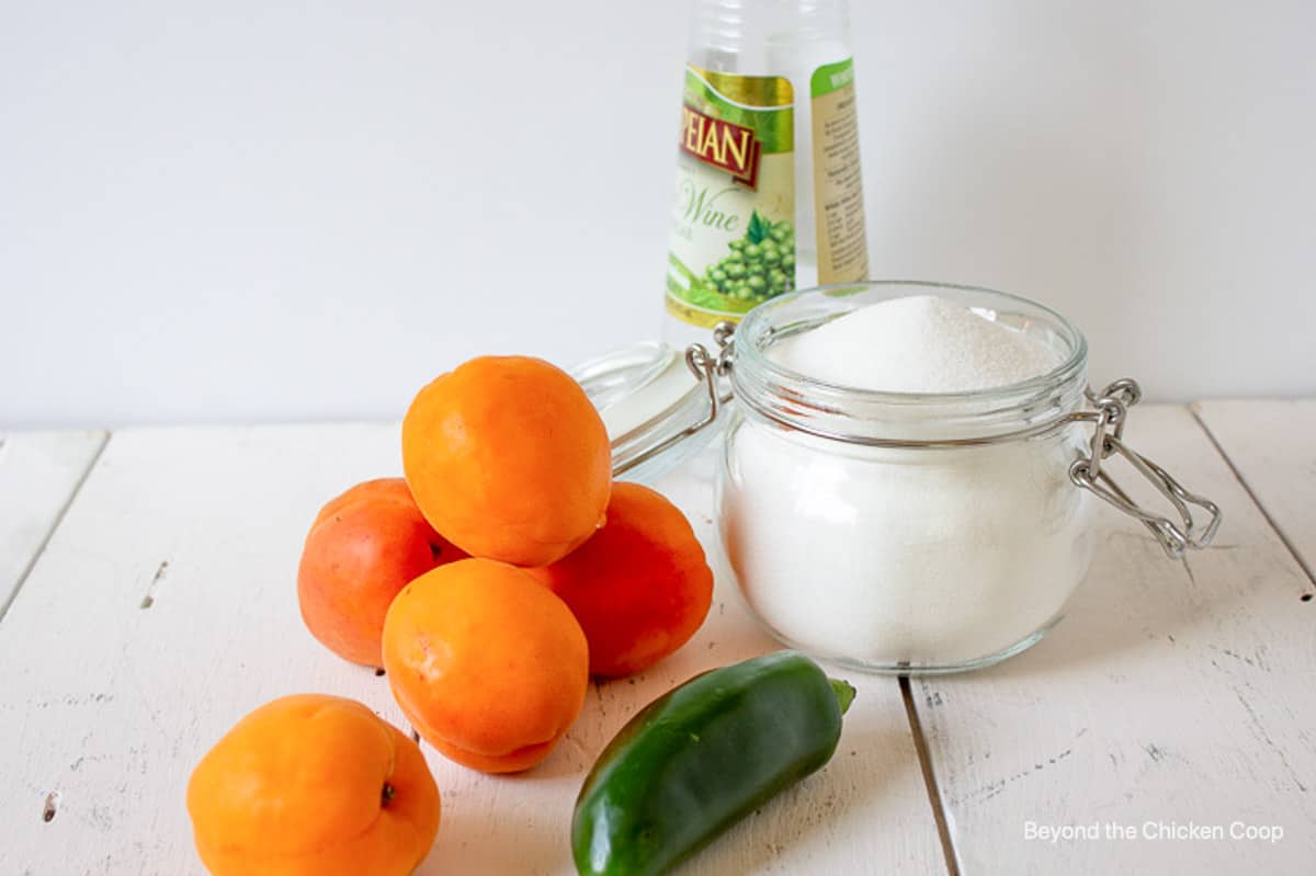 Apricots, jalapeno and sugar together on a board.