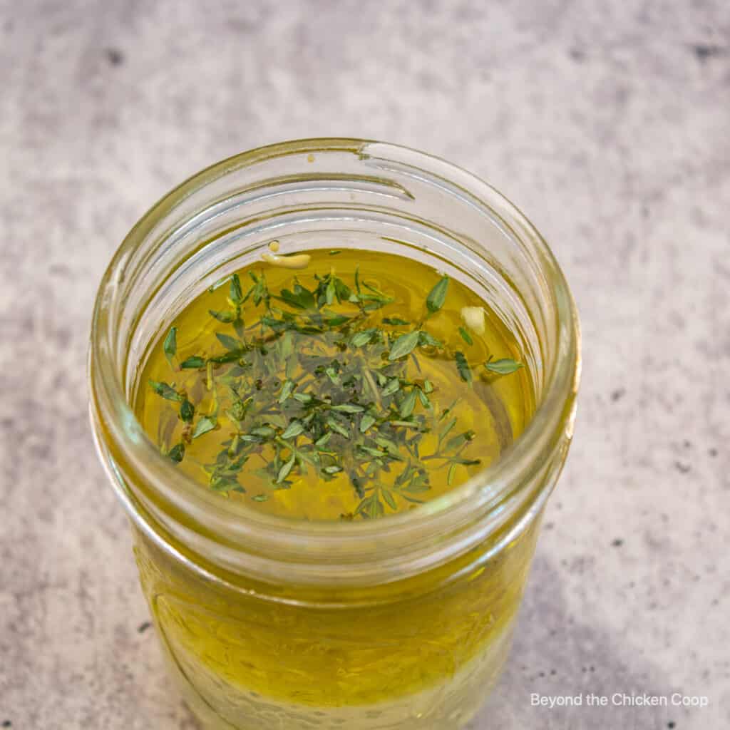 A jar filled with olive oil and herbs.