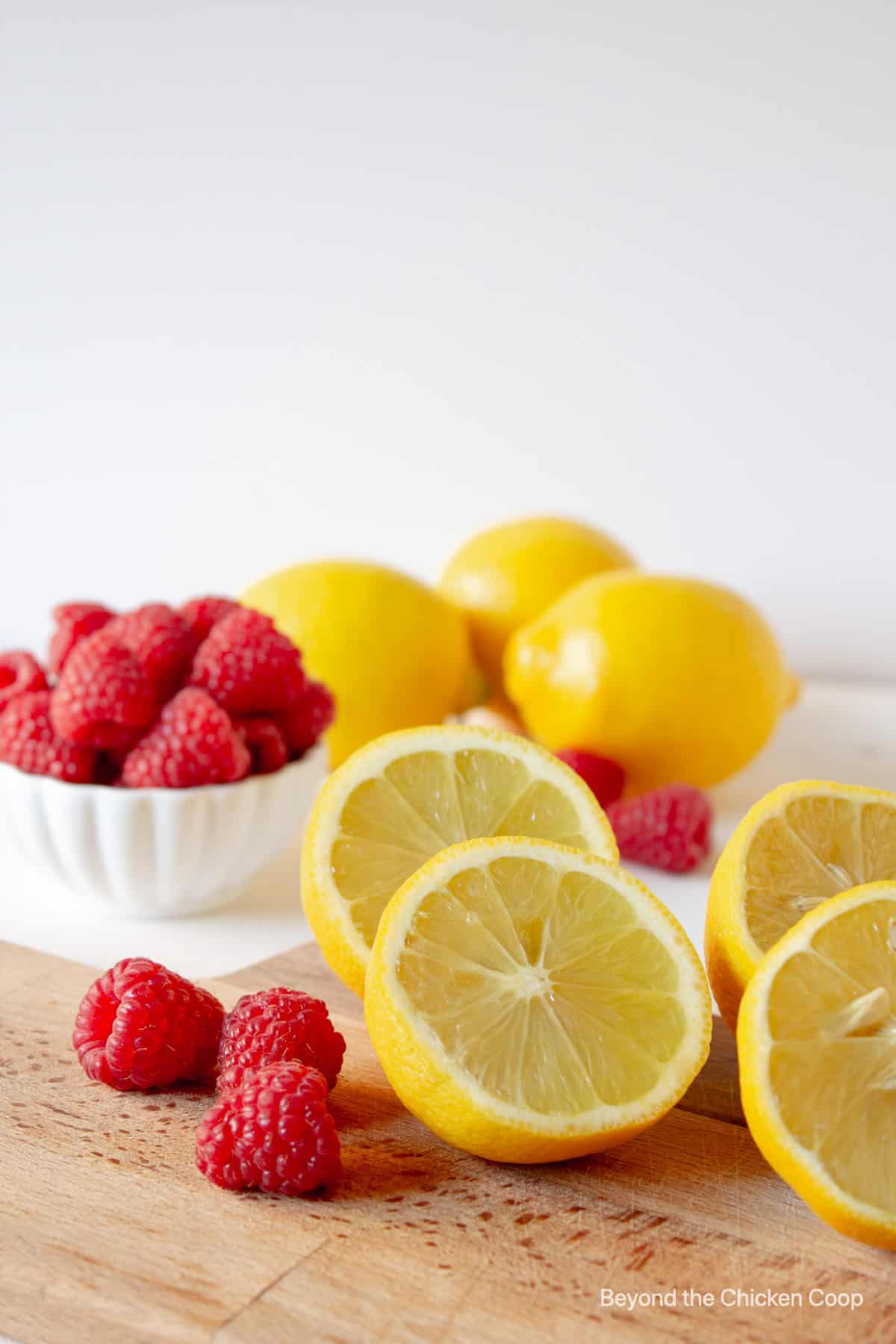 Fresh lemons and raspberries on a wooden board.