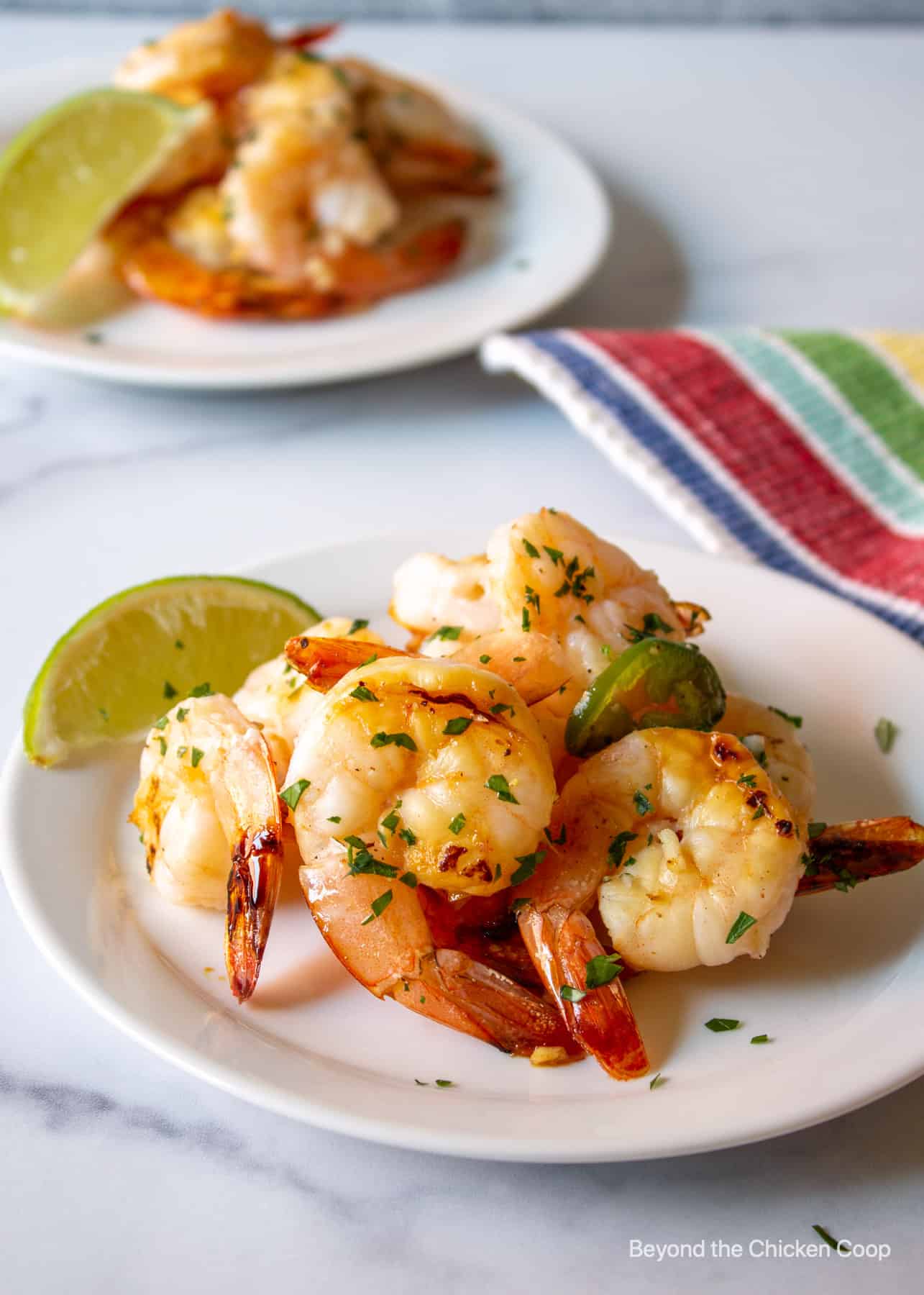 Grilled shrimp on a plate with a lime wedge.