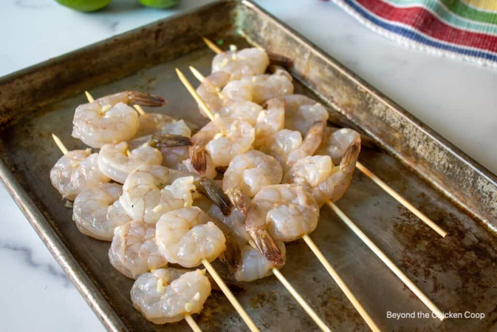 Skewered shrimp on a baking sheet.
