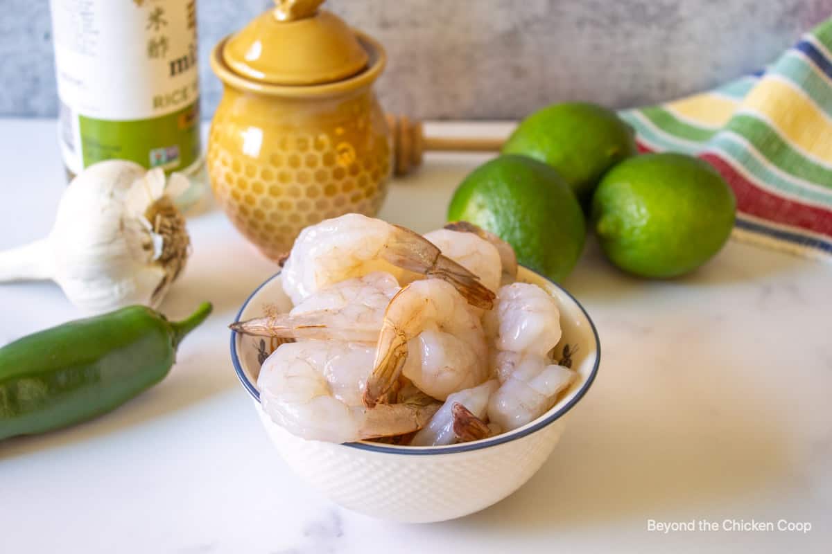 A bowl with shrimp next to fresh limes.