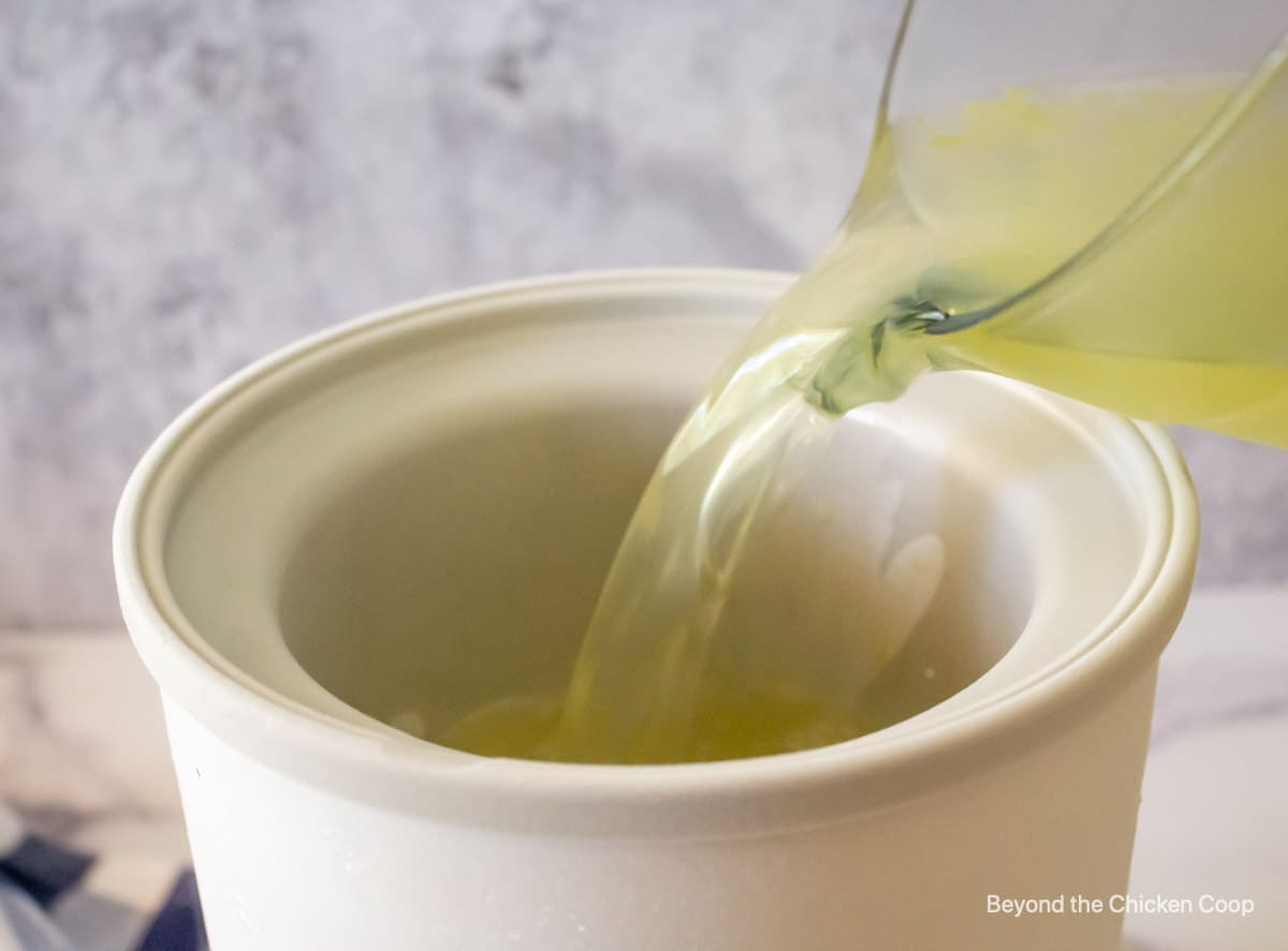 Pouring liquid into an ice cream mixing bowl.