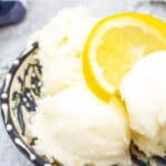 Scoops of a white sorbet topped with lemon slices.