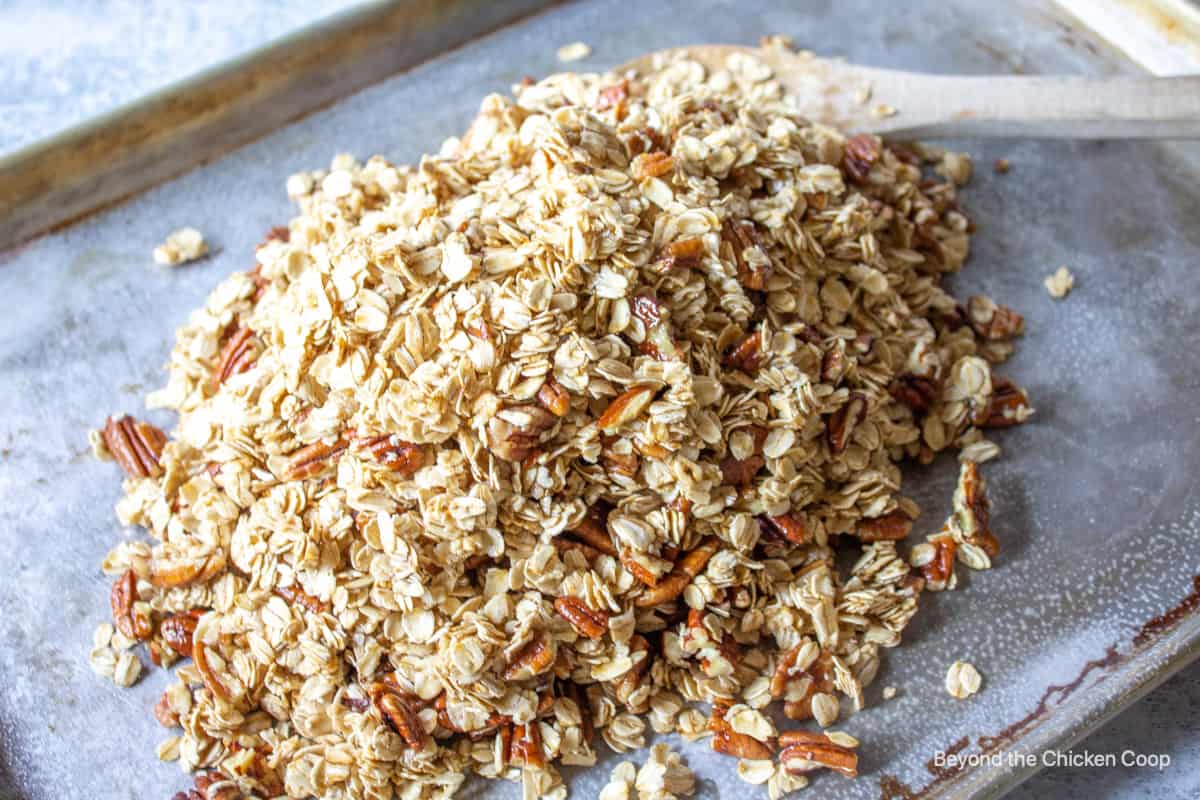 A pile of oats with pecans on a baking sheet.