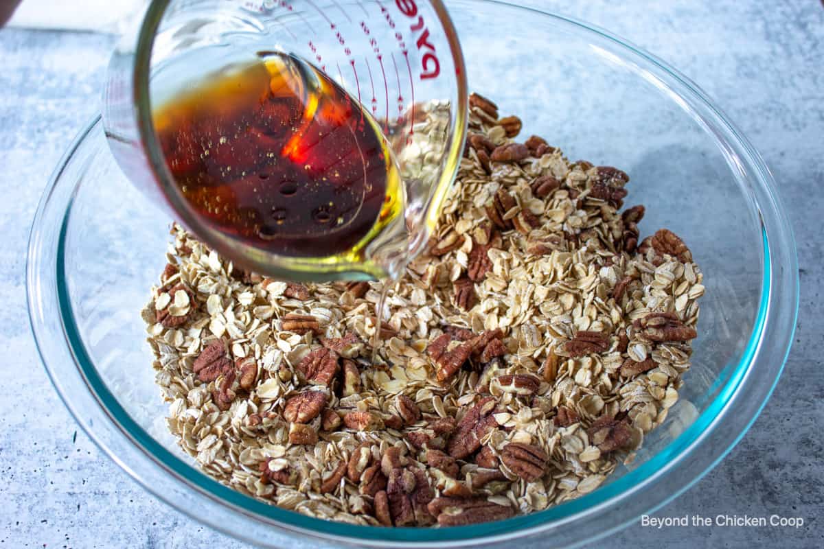 Pouring syrup over oats and pecans.
