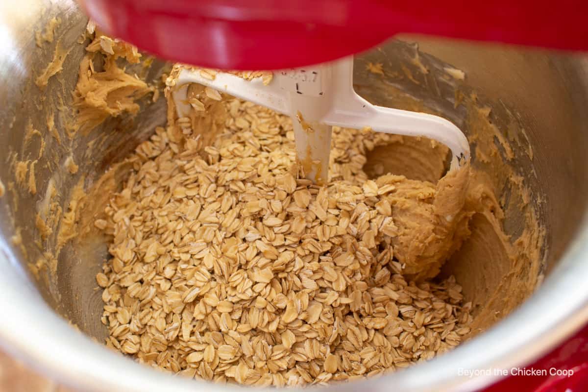 Oats added to a bowl with cookie dough.