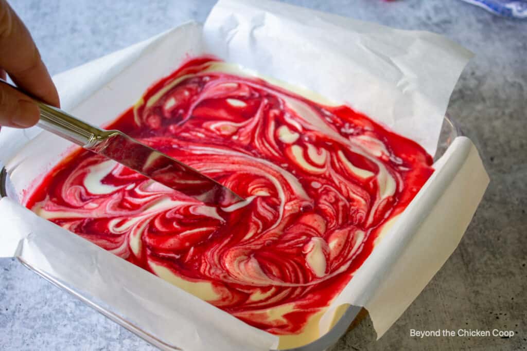 Swirls of raspberry sauce on cheesecake bars.