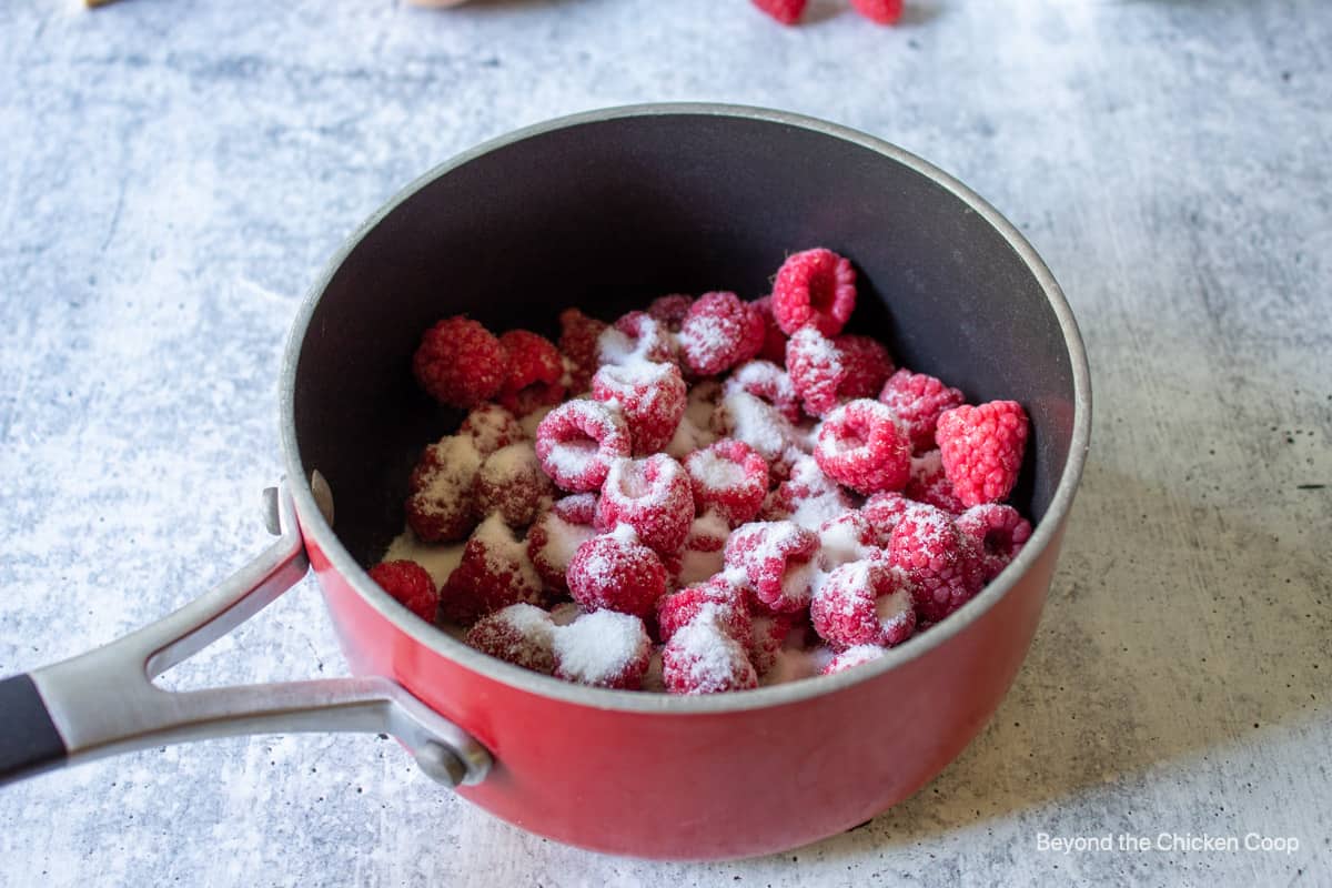 Raspberries and sugar in a pot.