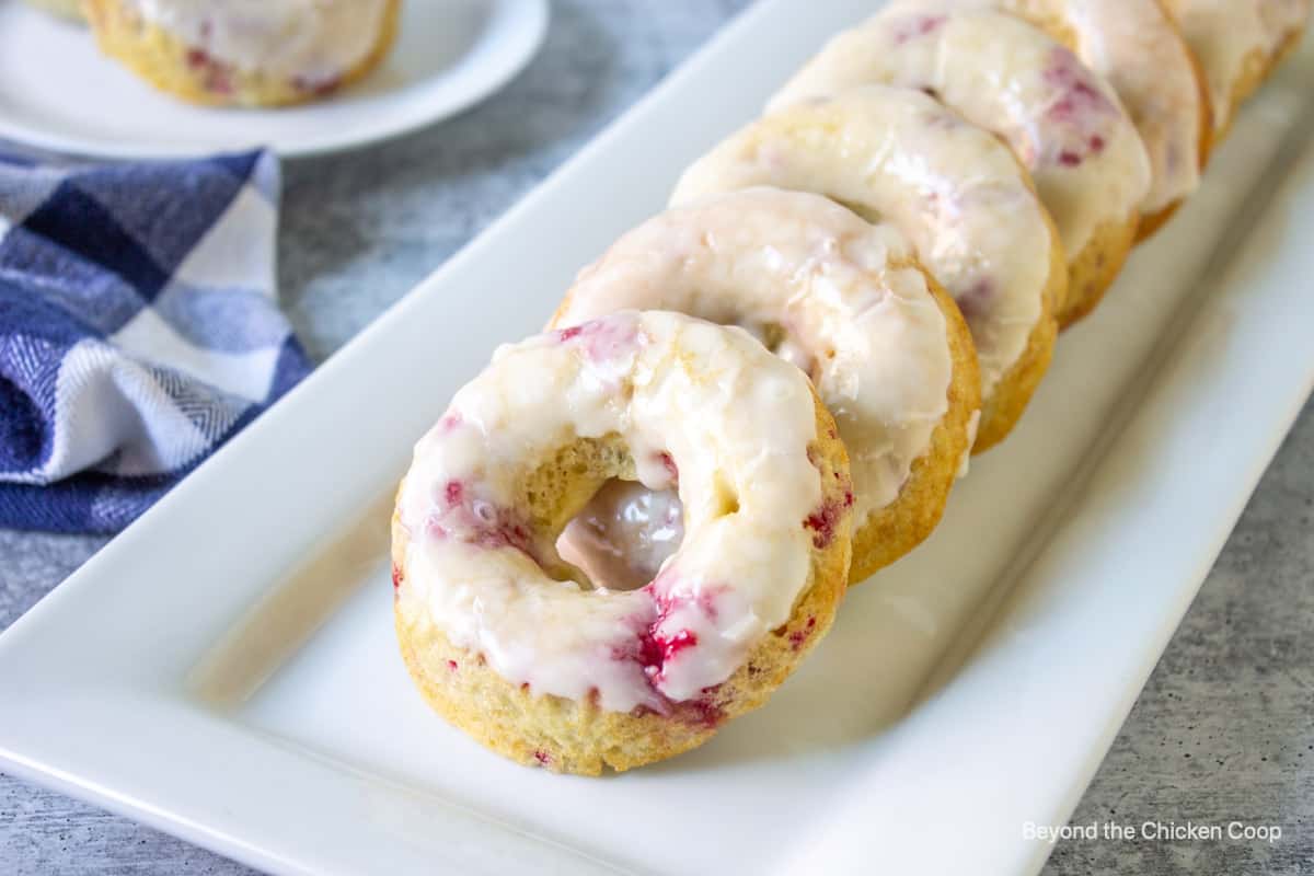 A row of raspberry donuts on a white platter.