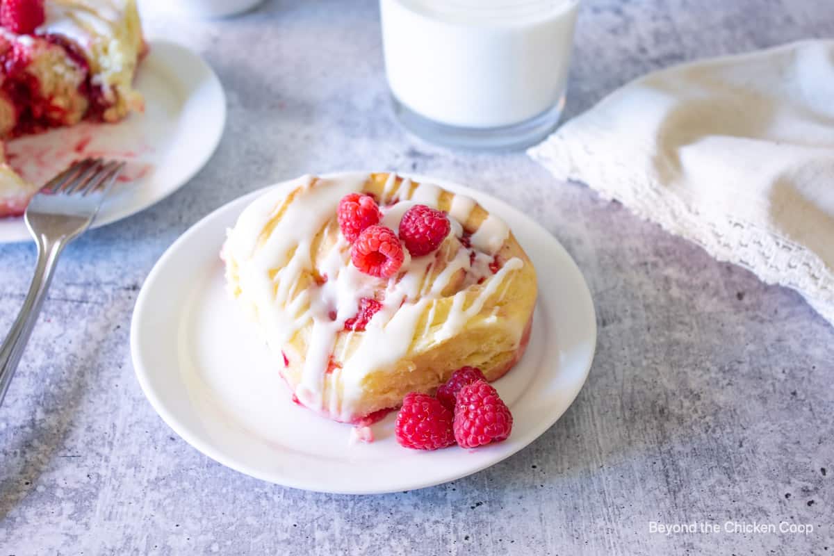 A sweet roll with raspberries on a plate. 