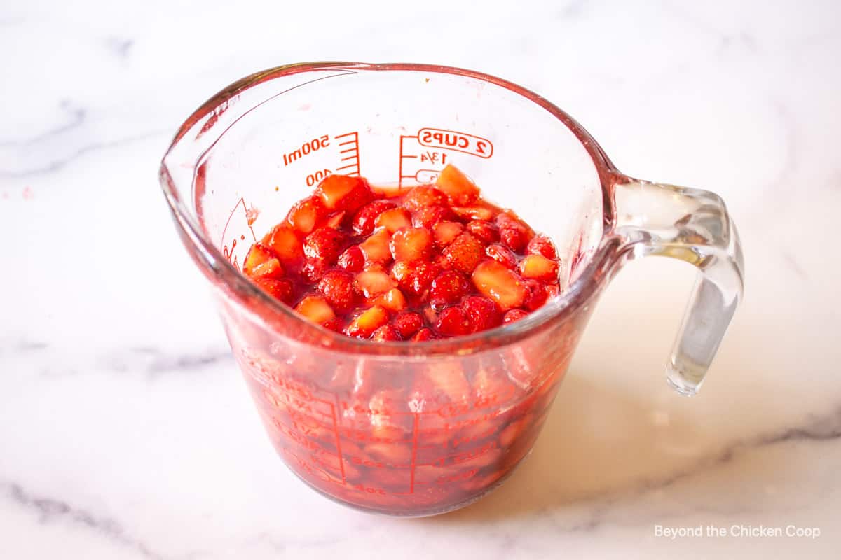 Macerated strawberries in a glass measuring cup.