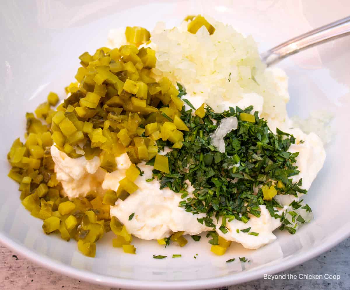 A bowl filled with mayonnaise and chopped pickles and onions.