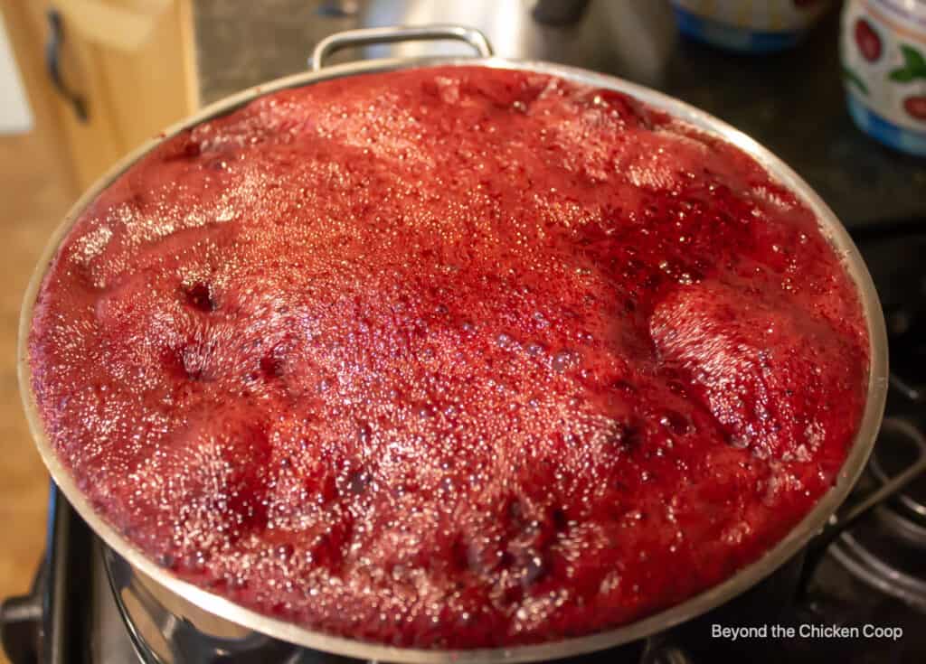 Blackberry jam boiling up to the top of the pot.