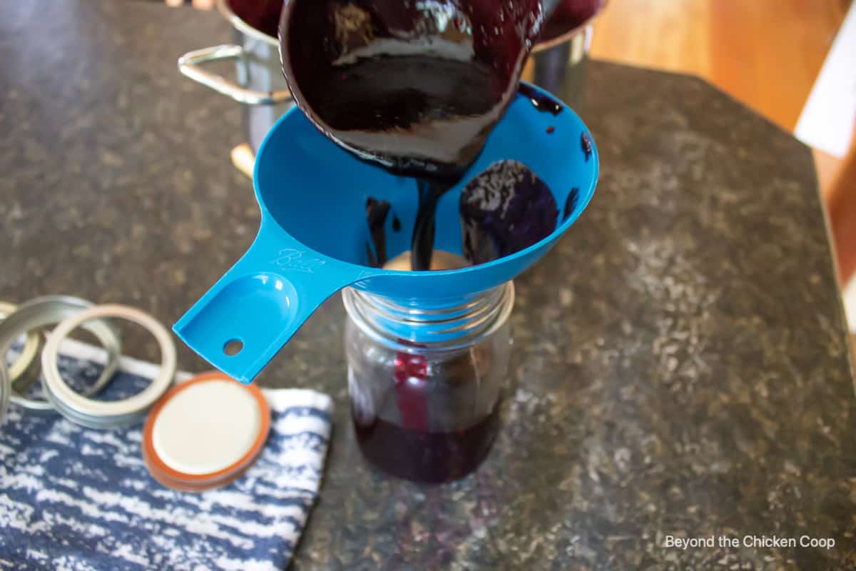 Jam being poured into a canning jar.