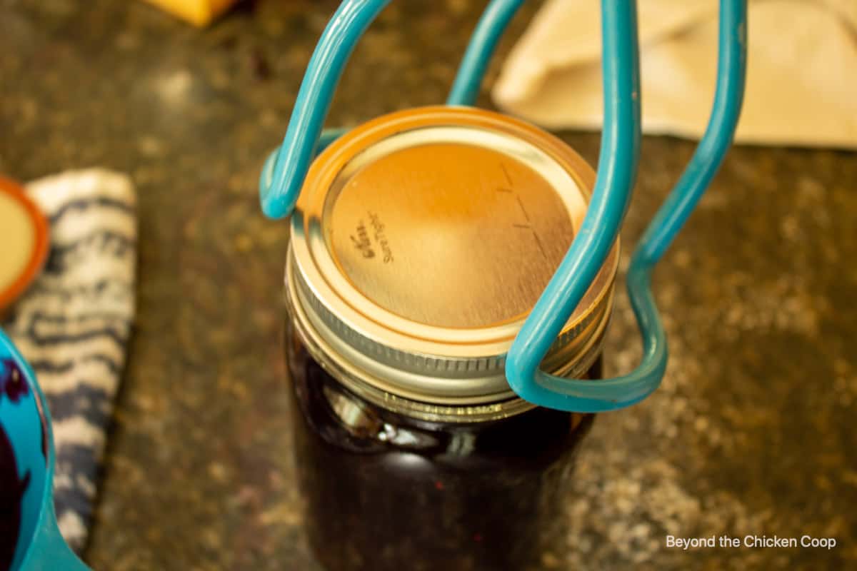 Using a jar holder to pick up a jar of jam.