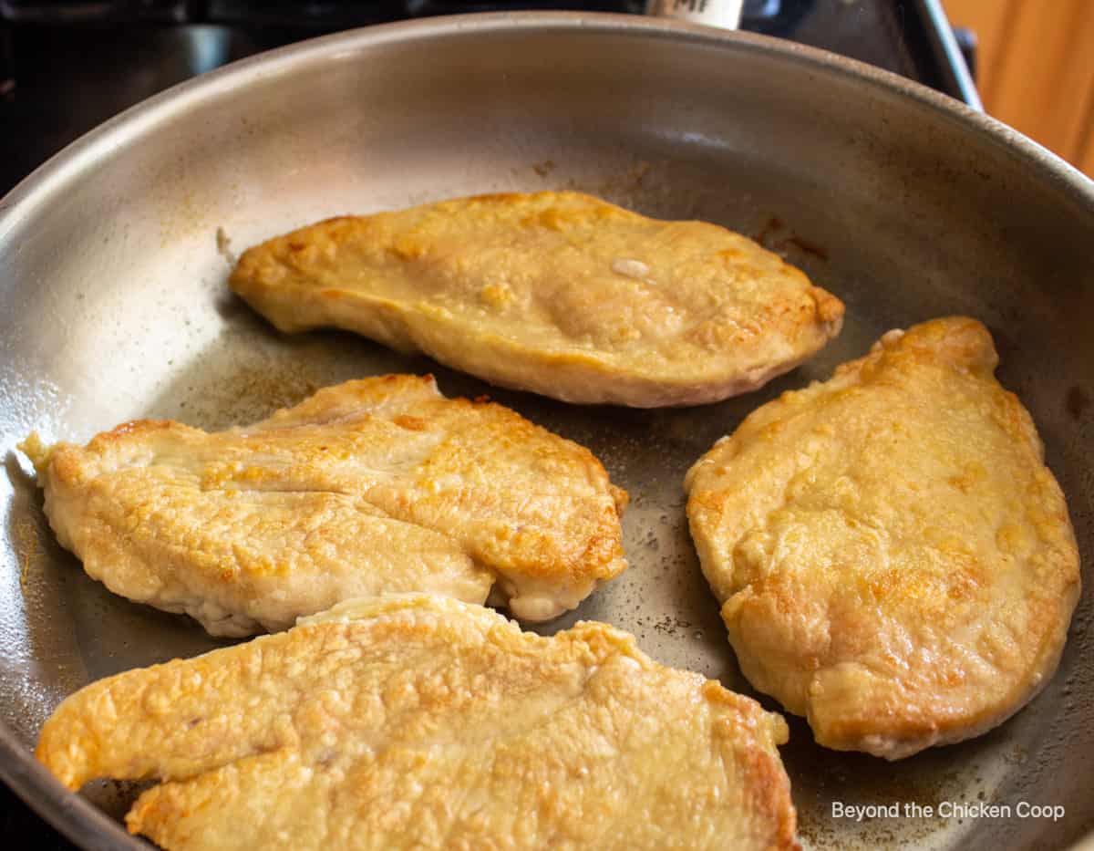 Browned chicken breasts in a pan.