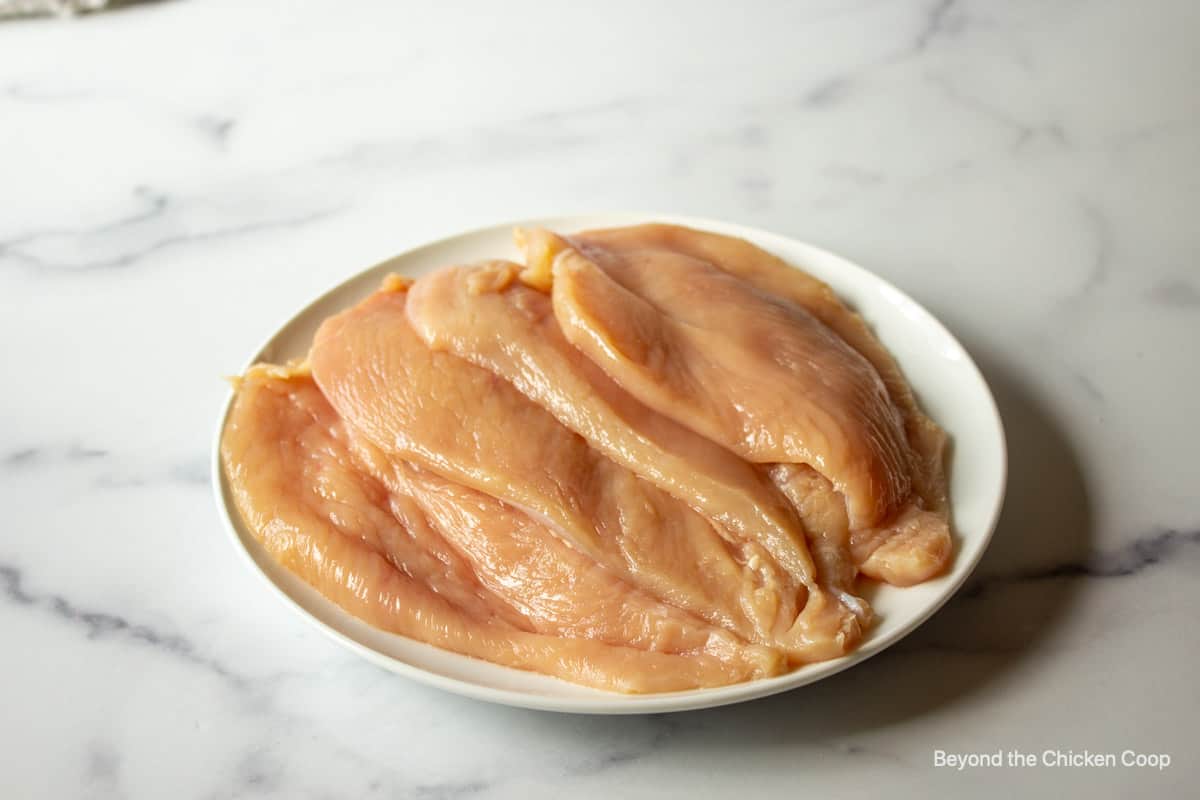 Four chicken breasts on a plate.