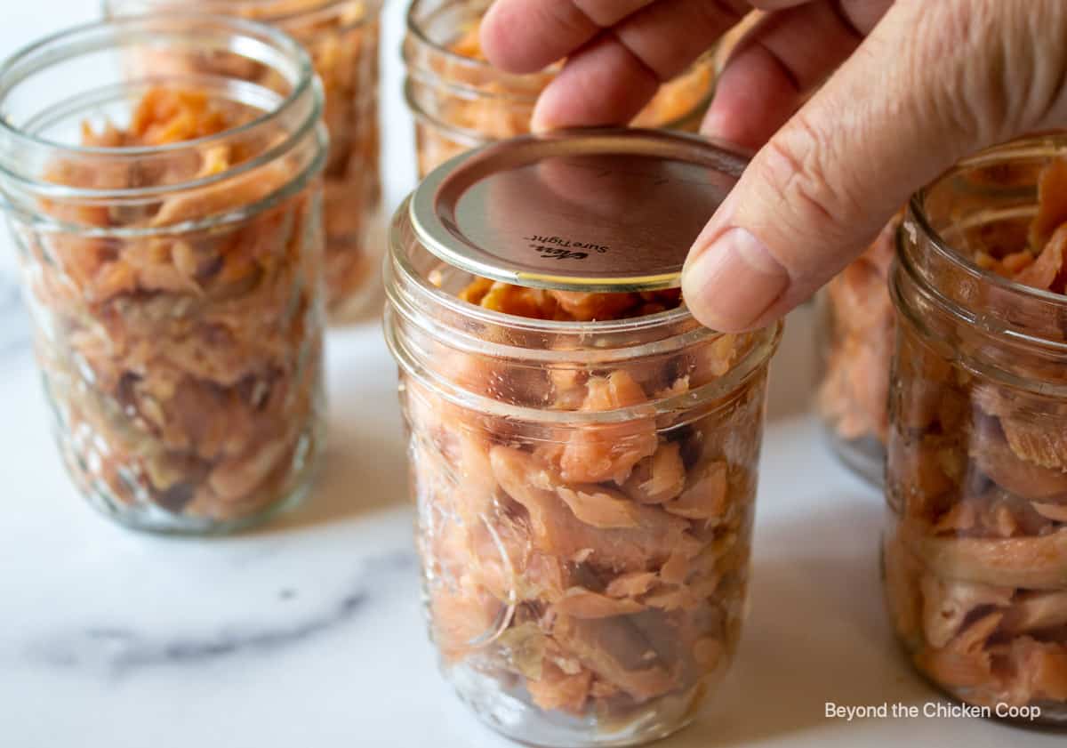 Placing a lid on a jar of fish.