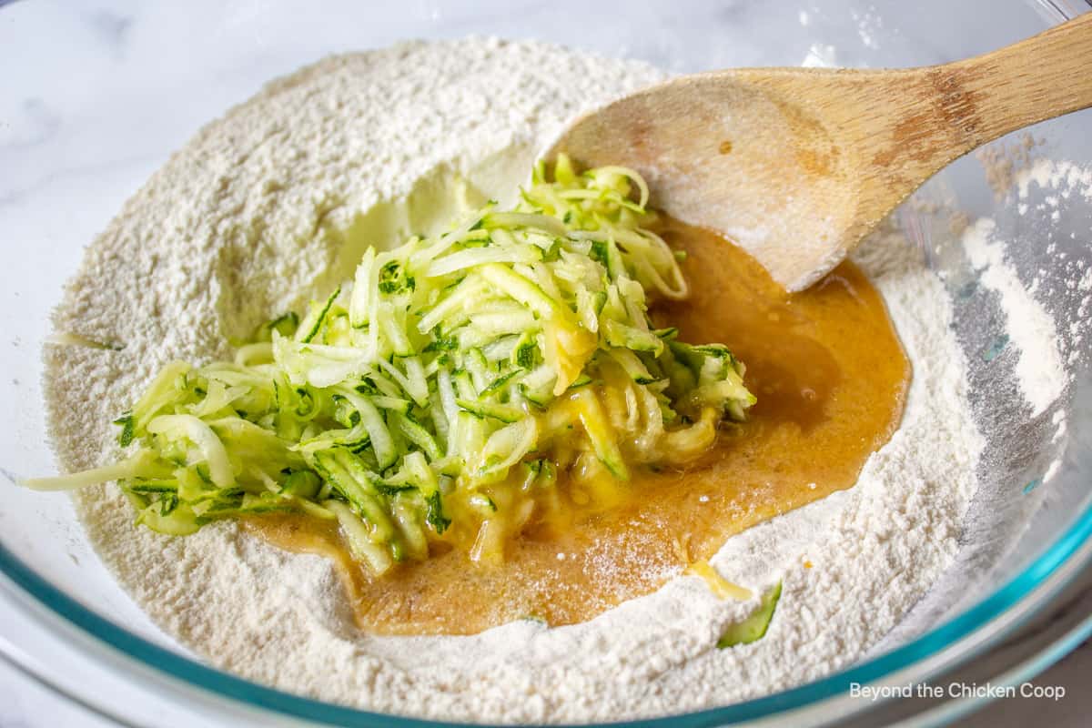 Grated zucchini added to a bowl of flour.